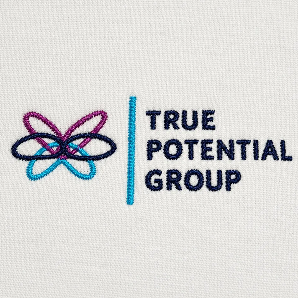 True Potential Group logo embroidered in navy, plum and turquoise on pale fabric